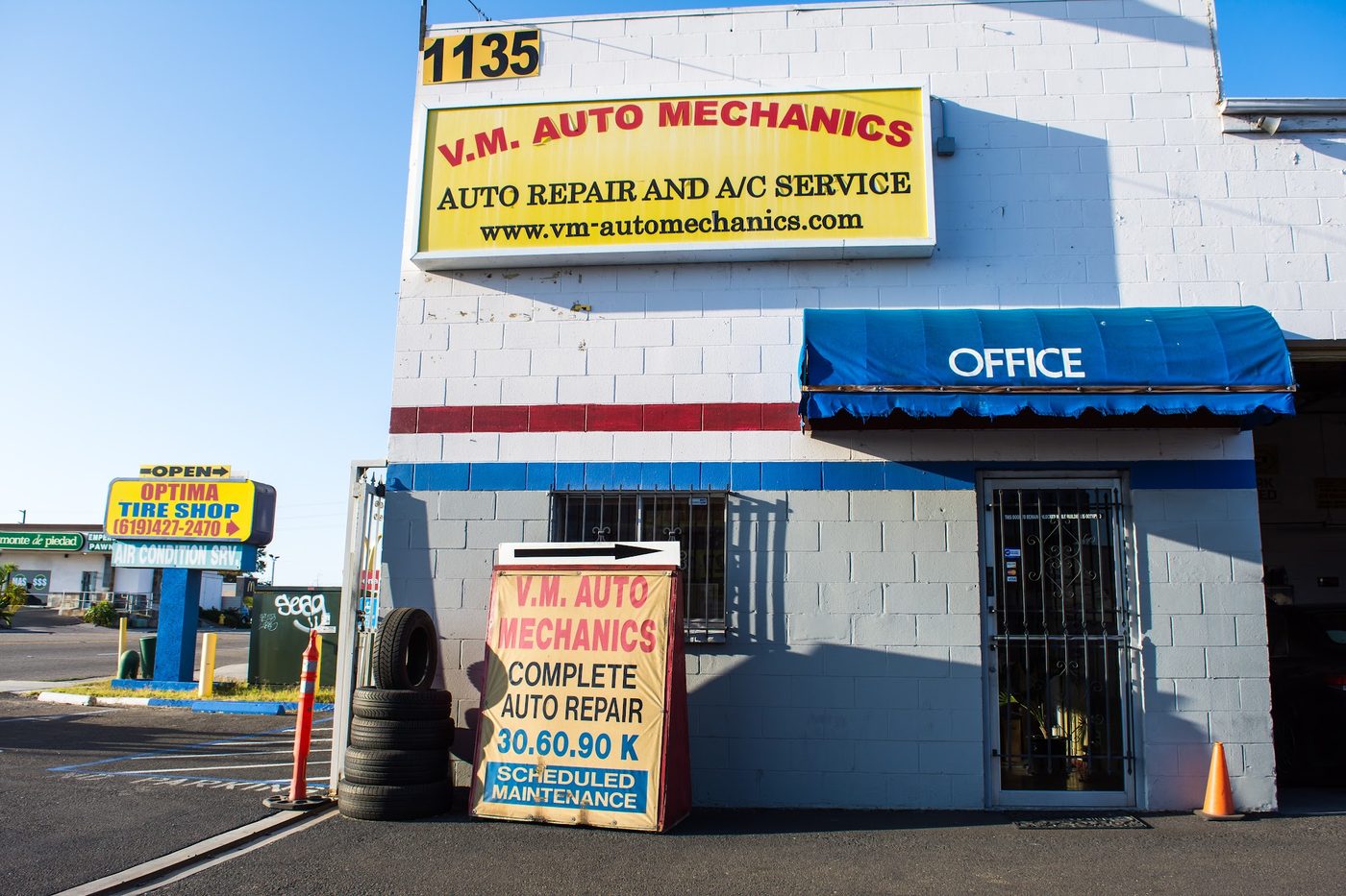 Corner of the shop with the A/C Service sign, office awning and 'Complete Auto Repair 30/60/90K Scheduled Maintenance' sign